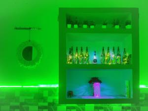 a green wall with shelves filled with bottles and a vase at Risabya Guest House in Gājol