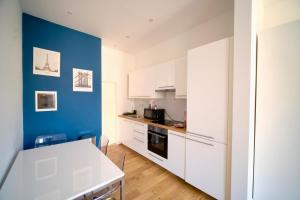 a kitchen with white cabinets and a blue wall at Easy Stay - City Center in Brussels +24 photos