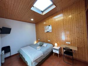 ein Schlafzimmer mit einem Bett und einem Dachfenster in der Unterkunft Pensión Codesal in O Pedrouzo