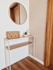 a mirror on a wall above a white shelf at Apartament Gniezno Bulwary 7a in Gniezno