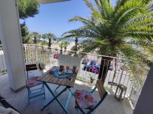 une table et des chaises sur un balcon avec un palmier dans l'établissement Sea Home Sunrise, à Tortoreto Lido
