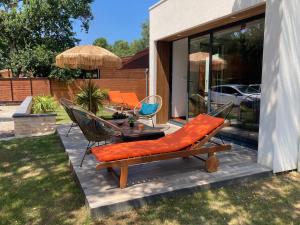 a patio with a bench and a table and chairs at Magnifique Maison architecturale à l'Océan in Labenne