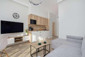 a living room with a couch and a tv at Cozy Studio with River View Spadochroniarzy with Parking & SPA by Noclegi Renters in Dziwnów