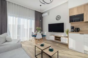 a living room with a couch and a table with chairs at Cozy Studio with River View Spadochroniarzy with Parking & SPA by Noclegi Renters in Dziwnów
