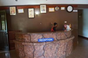 a man sitting at a reception counter in a large log at Peniel Beach Hotel in Entebbe