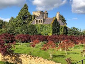an ivy covered building on a hill with a garden at The Rudloe Near Bath - Marco Pierre White in Corsham