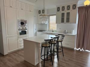 a kitchen with white cabinets and a white island with bar stools at Danydumbravita in Dumbrăviţa