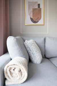 a gray couch with a white blanket on it at Rose Gold by Go Apart in Gdańsk +26 photos