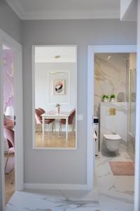 a white dining room with a table and a bathroom at Rose Gold by Go Apart in Gdańsk