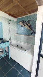 a bathroom with a tub with two dolphins on the wall at The Good Vibes Home in Hoya de Pineda