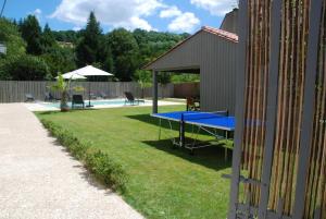 a ping pong table in a yard next to a pool at Le CLOS MARATUEL in Sarlat-la-Canéda