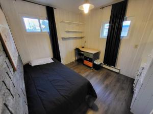 ein Schlafzimmer mit einem Bett und einem Schreibtisch und zwei Fenstern in der Unterkunft Suites On Chocolate - The Annville Cottage in Annville