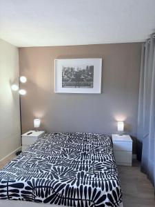 a bedroom with a bed with a black and white comforter at Appartement T2 avec Piscine 300m plage et crique in Le Pradet