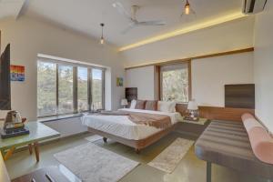 a bedroom with two beds and a couch and windows at Alaya Stays Adarsh Elegant 3-BHK Villa With Private Pool in Lonavala
