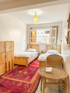 two beds in a room with a table and a rug at Single bed - Cozy dormitory - Surf territory in Agadir