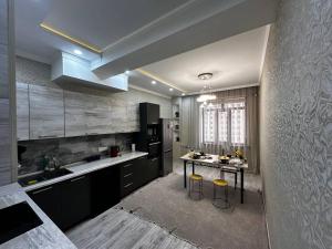 a kitchen with black cabinets and a table with stools at Spacious apartments in the center of Dushanbe in Isfisor