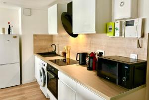 a kitchen with white cabinets and a black microwave at L'Eden - Hypercentre - 2 pers in Le Mans