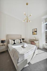 a white bedroom with a large bed and a chandelier at (G1) Elegant 2 bed Blythswood Apartment in Glasgow