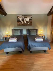 two beds in a room with two lamps on tables at Favau in Sainte-Radegonde