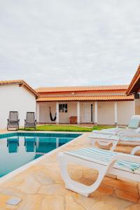 a pool with lounge chairs next to a house at Chácara Recanto Lunar in Boituva