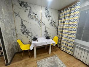 a dining room with a table and yellow chairs at Люкс квартира возле Керуен сити in Aktobe