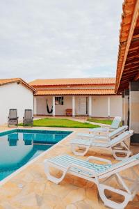 a group of lounge chairs next to a swimming pool at Chácara Recanto Lunar in Boituva