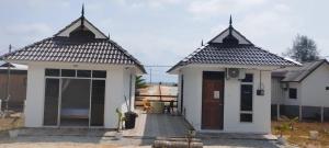 a small white house with a door in a yard at CC Roomstay Kampung Mangkuk, Terengganu in Setiu