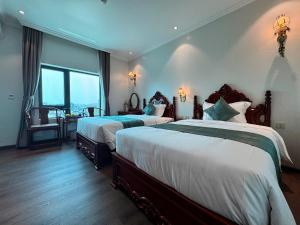 a bedroom with two beds and a table and a window at Trường Giang Hotel 2 in Móng Cái