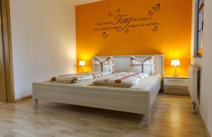 um quarto com uma cama branca e uma parede laranja em Ferienwohnung Storchennest em Bad Liebenstein