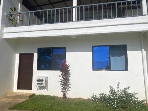 a white house with a balcony on top of it at Concetta Tourist Inn in Damilag +11 photos