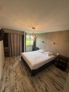 une chambre avec un grand lit et un lustre dans l'établissement Maison du manoir, à Bénouville