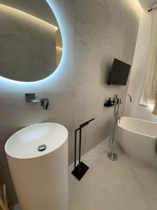 a bathroom with a sink and a tub and a mirror at Nonna Ciccina House in Pachino