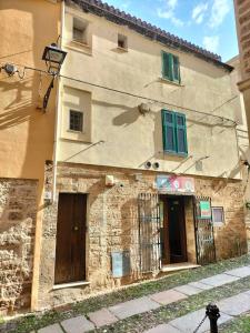 an old stone building with green windows and a street at Il Ginepro in Alghero