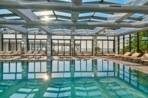 a swimming pool with lounge chairs and a large ceiling at GRIFID Encanto Beach Hotel - MediSPA, Ultra All Inclusive & Private Beach in Golden Sands +49 photos