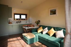 a living room with a green couch and a kitchen at Cuilcagh Cabins in Letterbreen