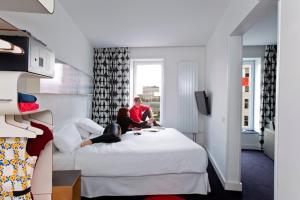 Dos personas sentadas en una cama en una habitación de hotel. en Hotel Gat Point Charlie, en Berlín