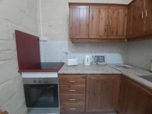 a small kitchen with wooden cabinets and a stove at Three Apartment in Vittoriosa