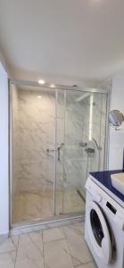 a glass shower in a bathroom with a washing machine at Beachfront Apartaments in Orbi City in Batumi
