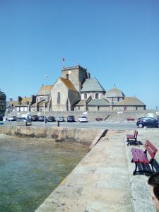 a group of benches sitting next to a body of water at La MAISON DU PECHEUR in Barfleur