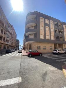 Un coche rojo aparcado delante de un edificio en Brisa del mar, en Torrevieja