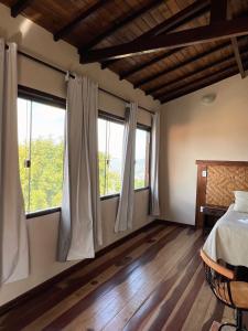 - une chambre avec deux fenêtres, un lit et du parquet dans l'établissement Vista da Serra, à Lavras Novas