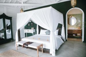 a bedroom with a white bed with a canopy at White Tortoise Eco Villa's in Uluwatu +74 photos
