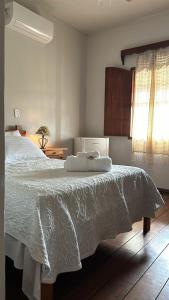 um quarto com uma cama branca e uma janela em Pousada Elisa em Tiradentes