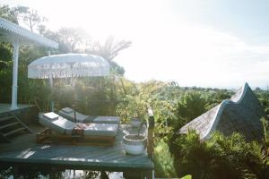 a wooden deck with a chair and an umbrella at White Tortoise Eco Villa's in Uluwatu
