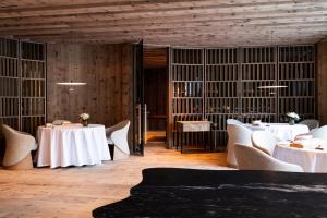 a restaurant with white tables and chairs and wooden walls at Gardena Grödnerhof - Hotel & Spa in Ortisei +43 photos