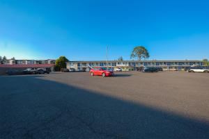 a red car parked in a parking lot in front of a building at OYO Hotel St Helens OR in Saint Helens