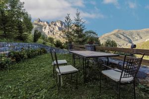 a table and chairs sitting in the grass with mountains at La Posada de Cucayo in Dobres