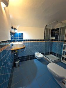 ein blau gefliestes Badezimmer mit Waschbecken und Toilette in der Unterkunft Sardinian Gallery Seminario in Bosa
