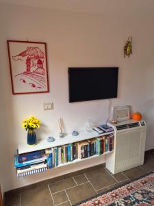 ein Flachbildfernseher über einem Bücherregal mit Büchern in der Unterkunft Sardinian Gallery Seminario in Bosa + 18 Fotos
