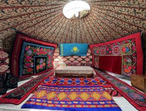 a room with a bed and a ceiling with colorful carpet at Bakytzhan hotel in Kurmenty